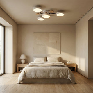 Minimalistická ložnice s dvojlůžkem, dvěma nočními stolky, stolními lampami a stropním svítidlem nad postelí.